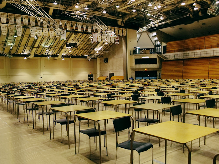 Rows and rows of desks set up in a large auditorium.